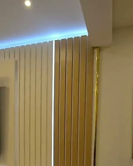 Room-width cream slat wall with oak accents and LED cove, built by WK Home Interiors